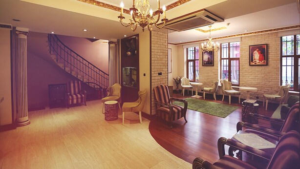 A spacious room with a grand chandelier, a staircase, and a seating area with multiple chairs and tables. - Nil Hotel Istanbul City Center (Istanbul)