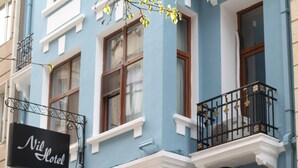 A hotel with a blue facade, black and white signage, outdoor seating, and a flag. - Nil Hotel Istanbul City Center (Istanbul)