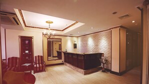 A hotel lobby with a reception desk, a chandelier, a brick wall, and seating area. - Nil Hotel Istanbul City Center (Istanbul)