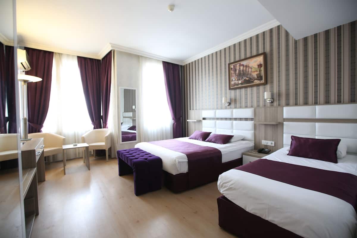 A hotel room with two beds, a desk, and a chair.