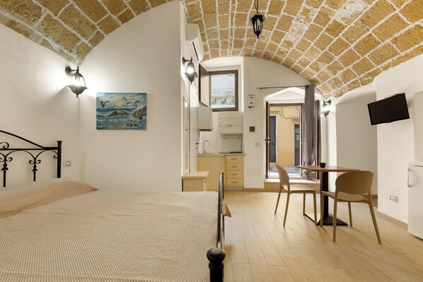 Un dormitorio con cama, escritorio y kitchenette.