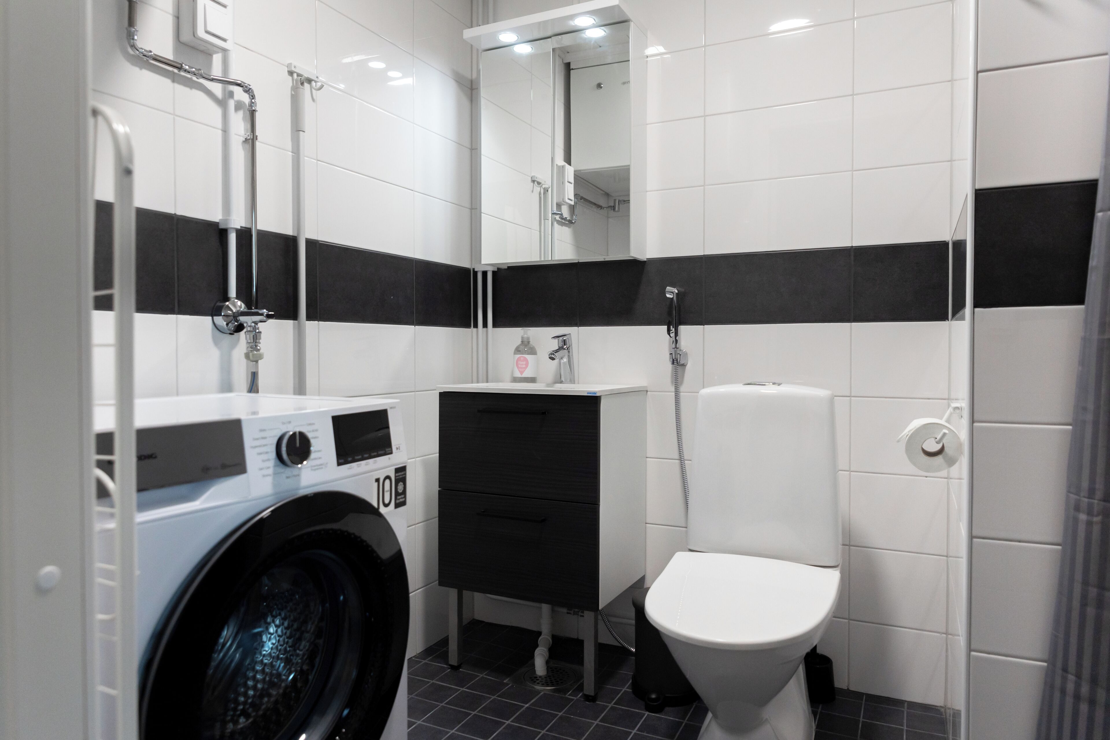 Ein modernes Badezimmer mit Waschmaschine, Waschbecken und Toilette.