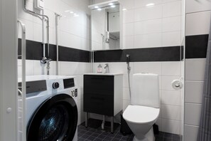 A modern bathroom with a washing machine, a sink, and a toilet. - Forenom Apts Lahti Hennala (Lahti)