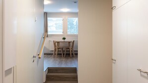 Una escalera conduce a una habitación con ventana y una mesa con sillas.