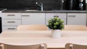 Una cocina moderna con armarios blancos, una mesa de madera y una planta en maceta.