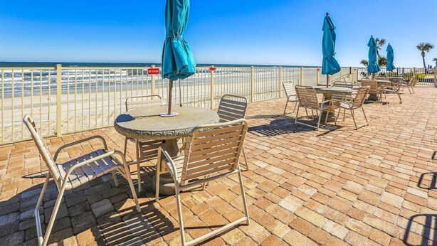 A seaside patio with outdoor seating, a 'NO DIVING' sign, and a view of the ocean. - Coquina Condos: Ocean View, Ground Floor (St. Augustine)