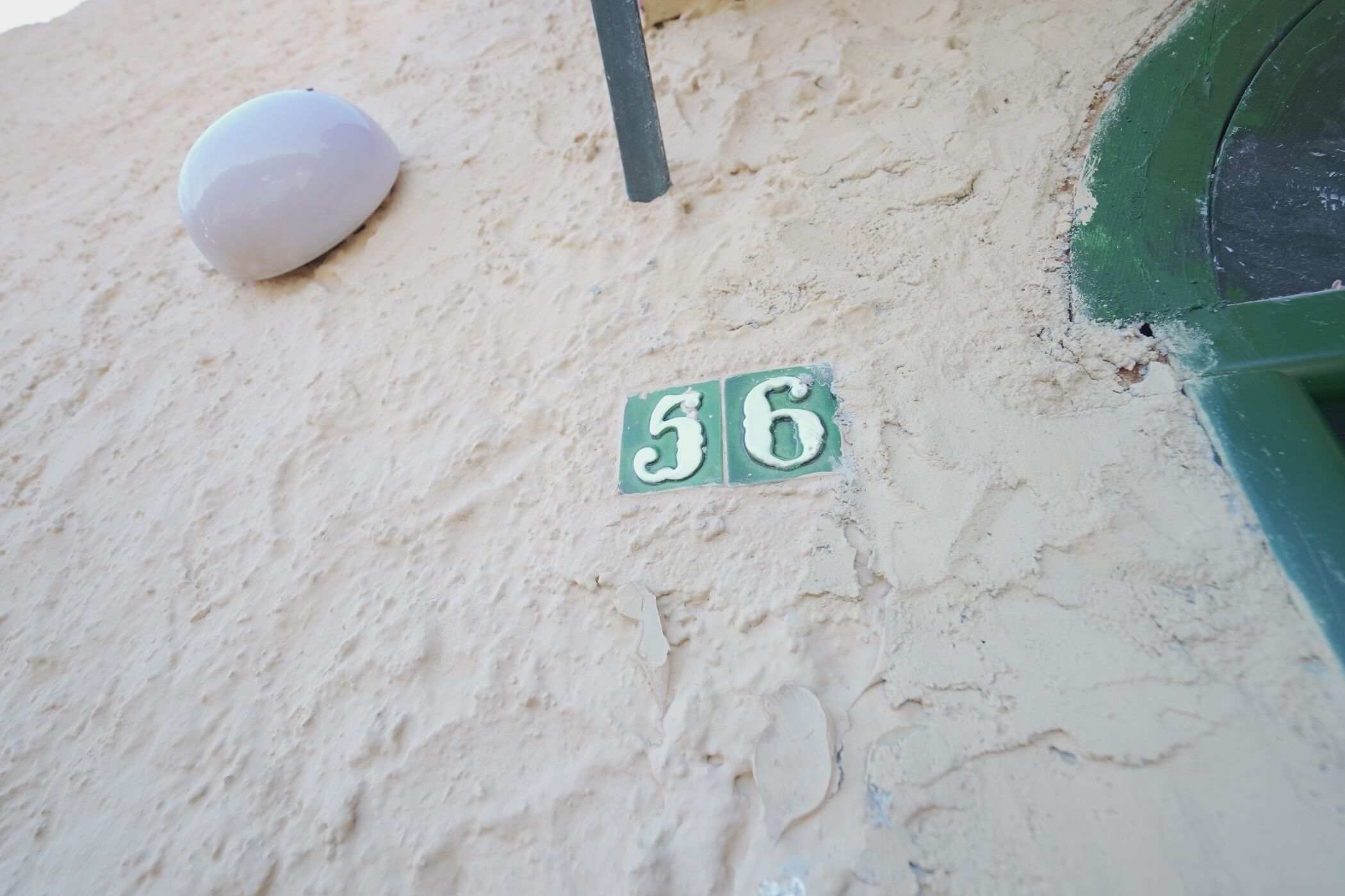 A number '56' on a wall, a white object, and a green structure.