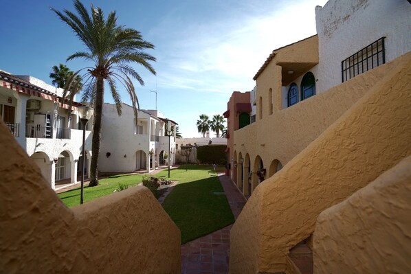 A courtyard with a palm tree, a tiled pathway, and buildings with arched doorways. - Sunstay Relax 56 Rio Marina Nerja (nerja)