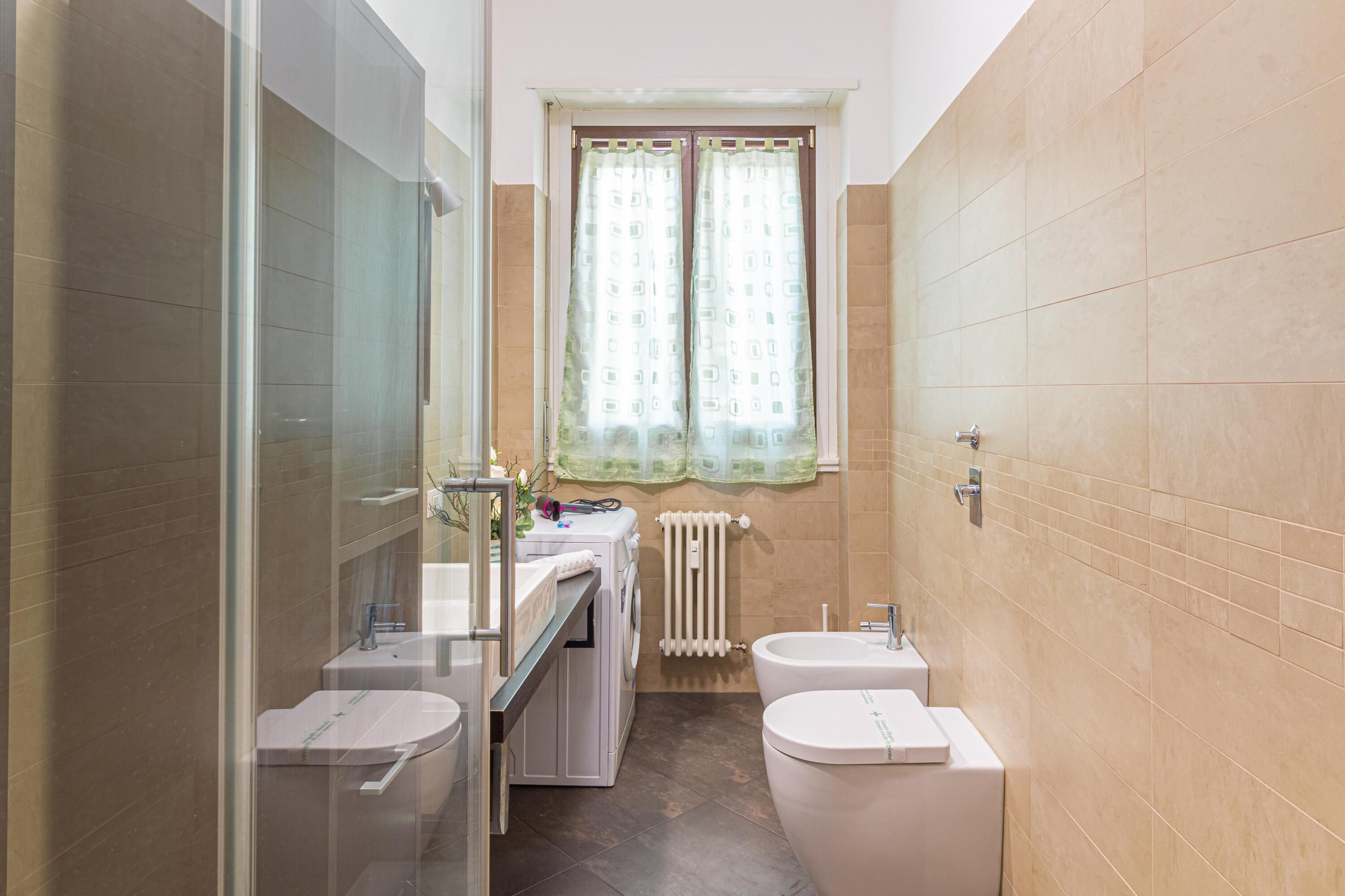 Ein kleines Badezimmer mit Duschkabine aus Glas, einem Waschbecken mit zwei Becken und einer Toilette.