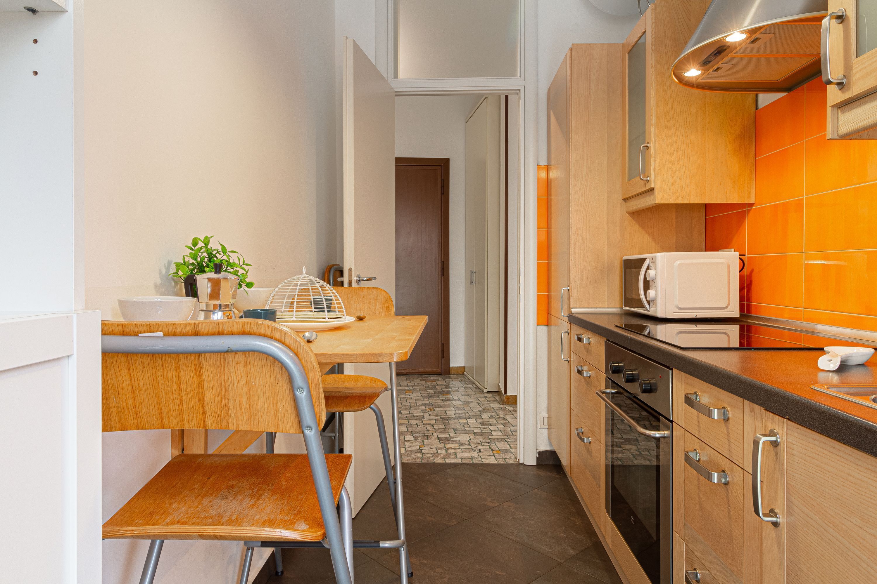 A compact kitchen with a dining area, featuring a microwave, oven, and a small table with chairs.