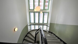 A spiral staircase with a handrail, a light fixture, and a window with blinds. - Forenom Serviced Apartments Kuopio (Kuopio)