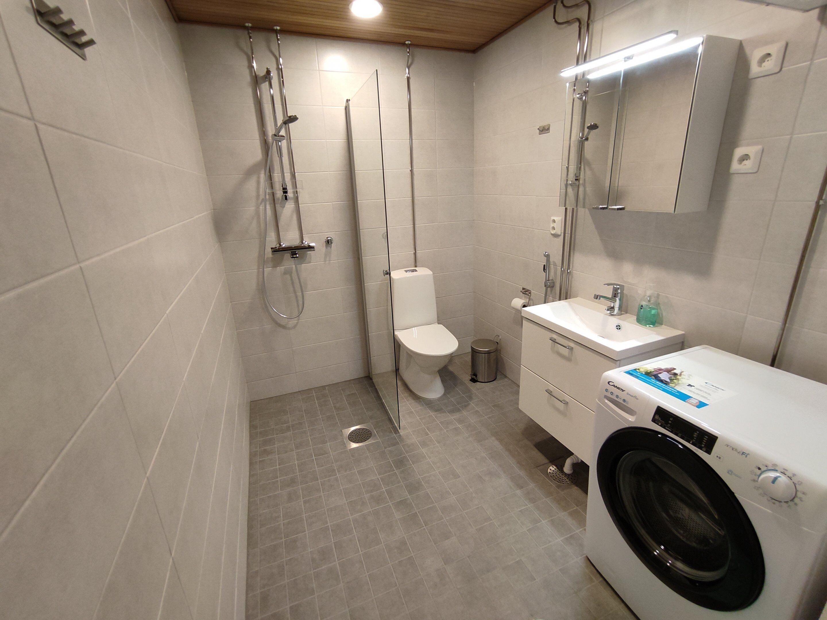 Un baño pequeño con inodoro, ducha y lavadora.