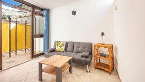 Ein modernes Wohnzimmer mit einem grauen Sofa, einem Holztisch und einem Korbtisch.