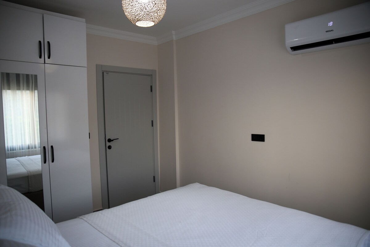 A bedroom with a bed, wardrobe, and an air conditioning unit.