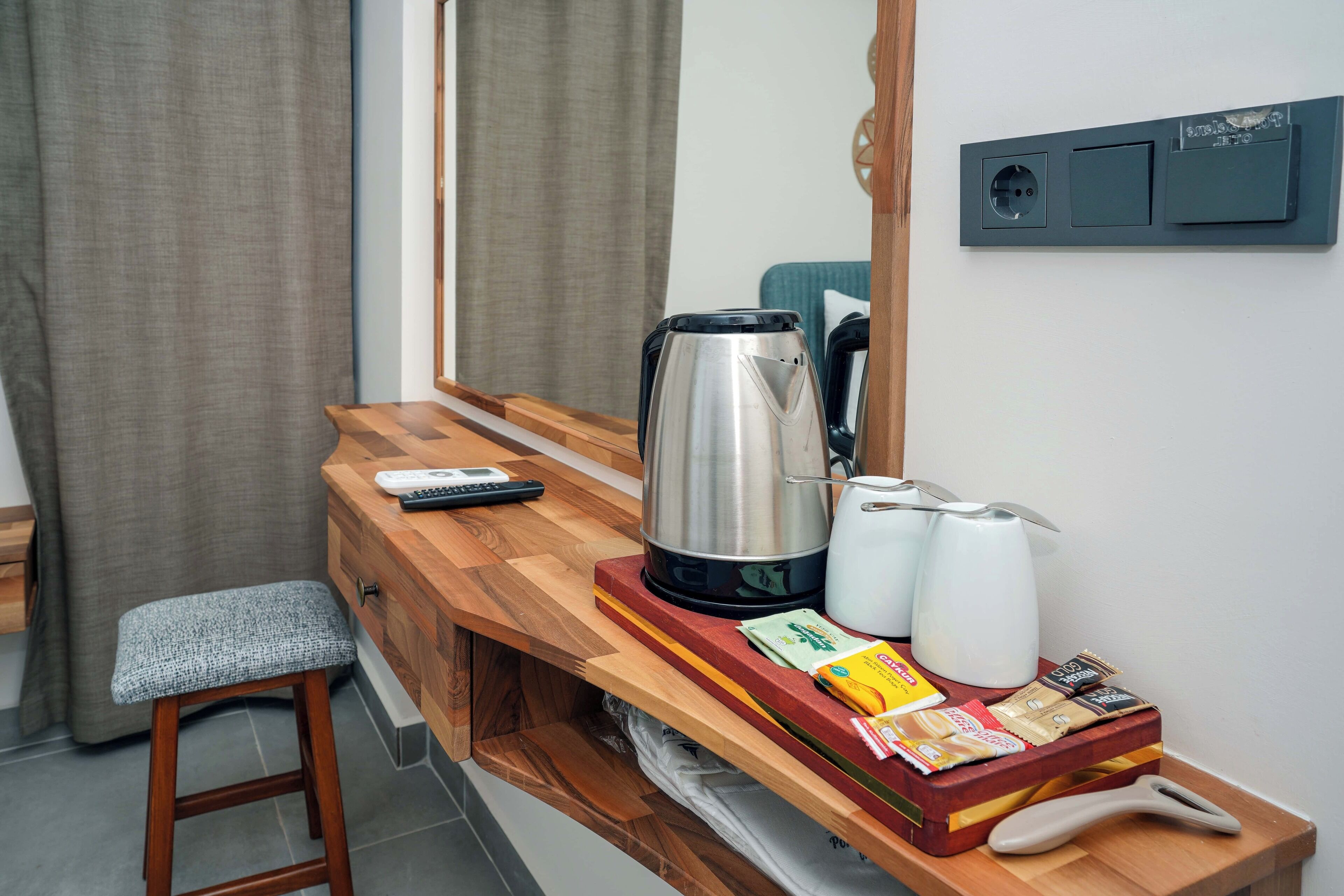 A compact kitchenette with a coffee maker, kettle, and tea pot on a wooden countertop.