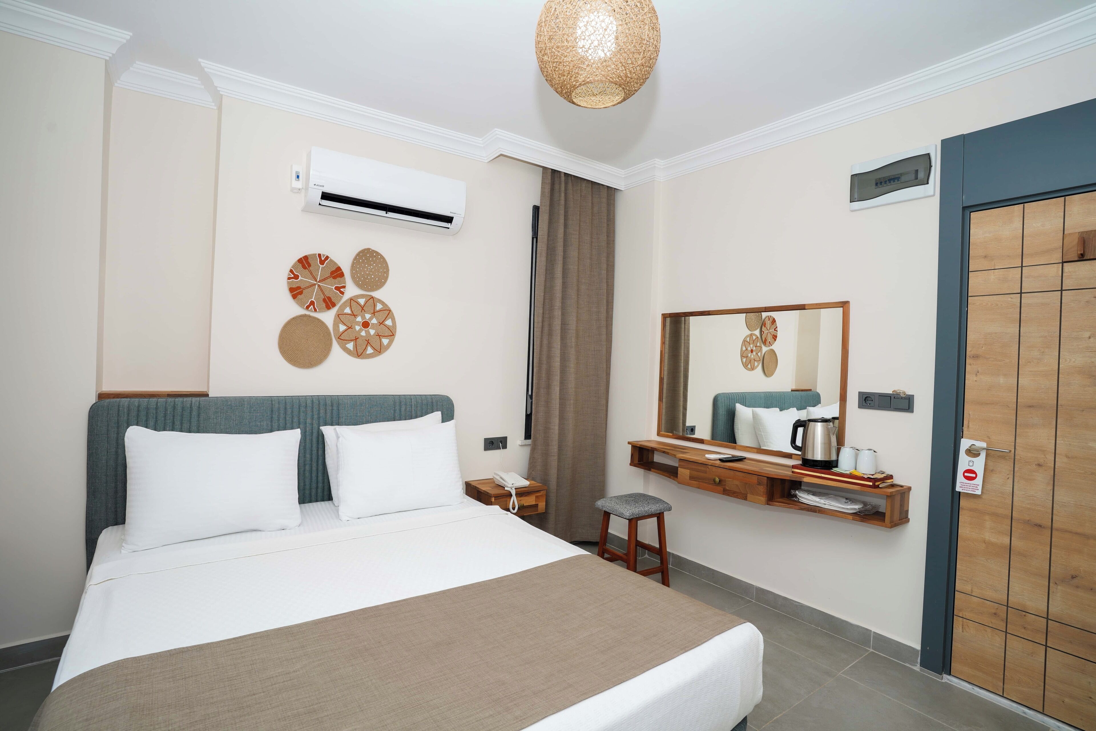 A hotel room with a bed, bedside table, mirror, and a wardrobe.