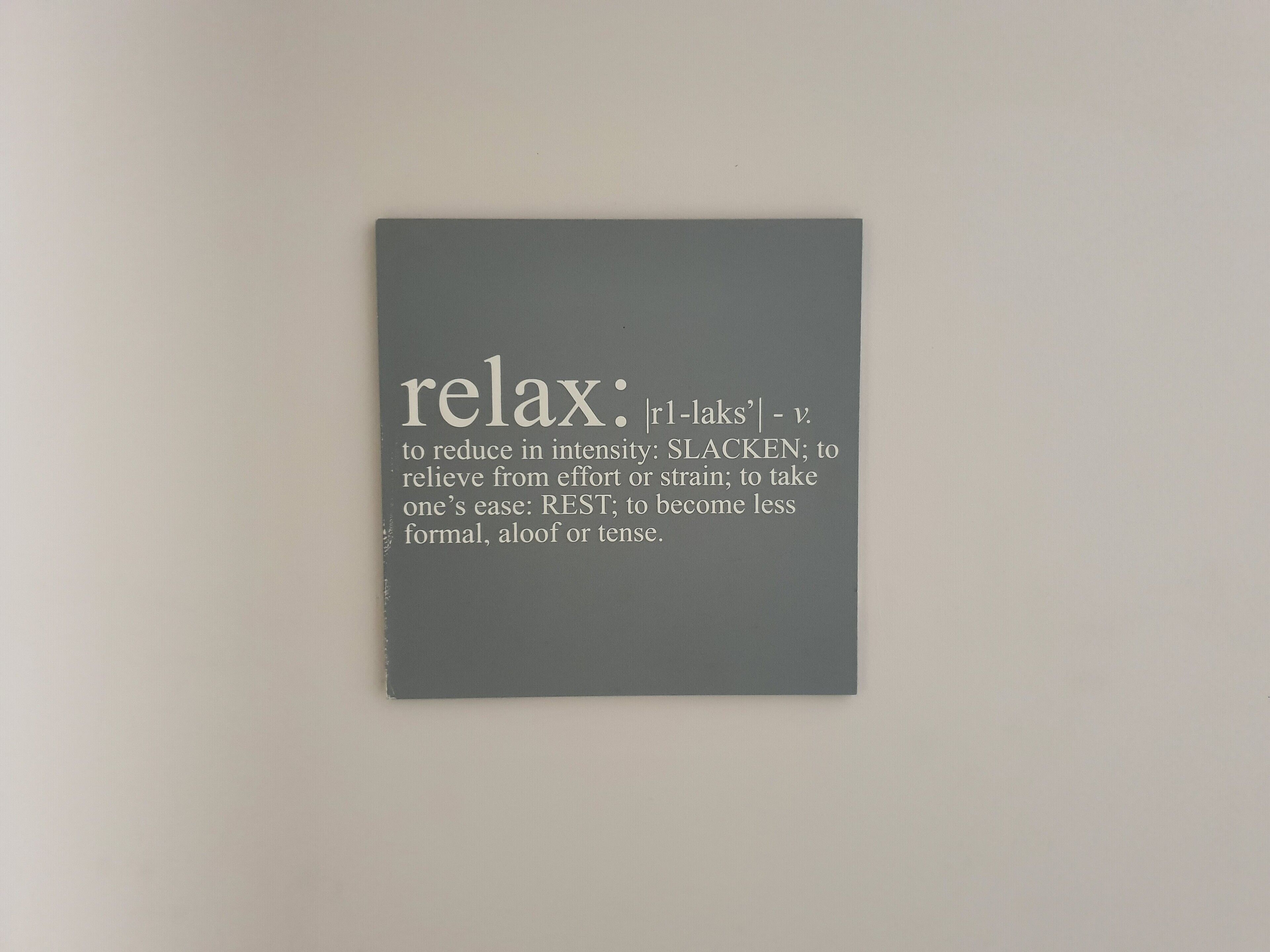 A gray sign with the word 'relax' and its definitions.