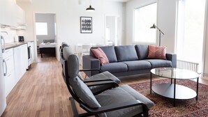 Ett modernt vardagsrum med en grå soffa, ett soffbord i glas och en mönstrad matta.