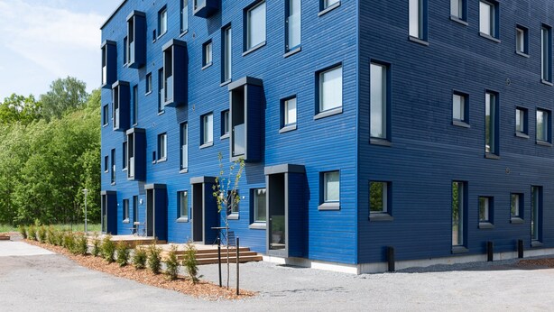 En modern blå byggnad med många fönster och balkonger.
