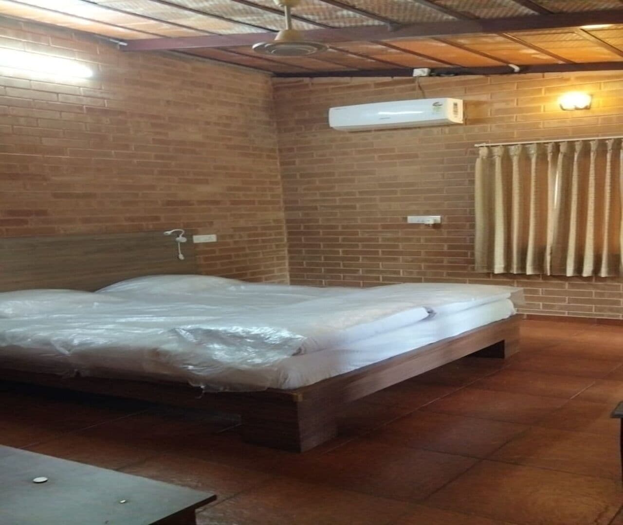 A room with a single bed, a table, and a brick wall.