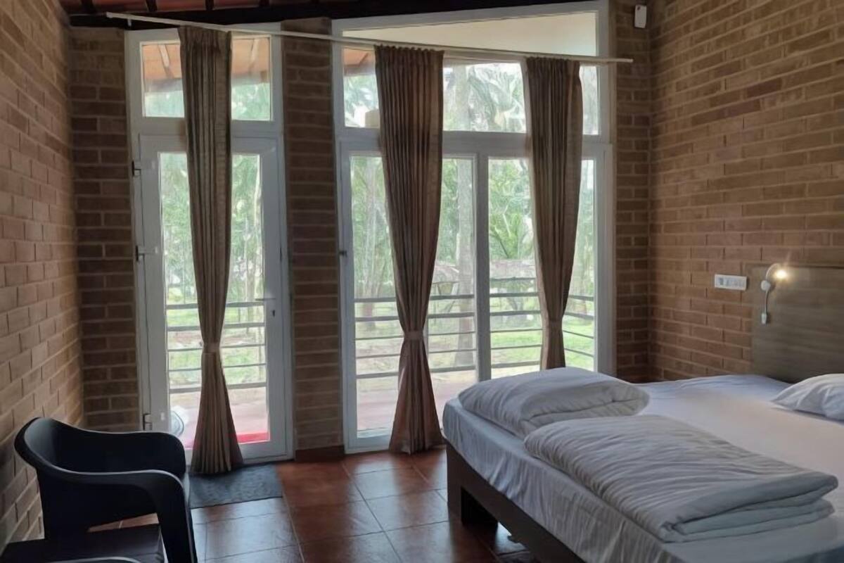 A bedroom with a bed, a chair, and a sliding glass door leading to an outdoor area.