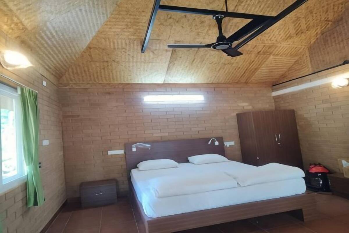 A bedroom with a wooden ceiling, a bed, a wardrobe, and a ceiling fan.