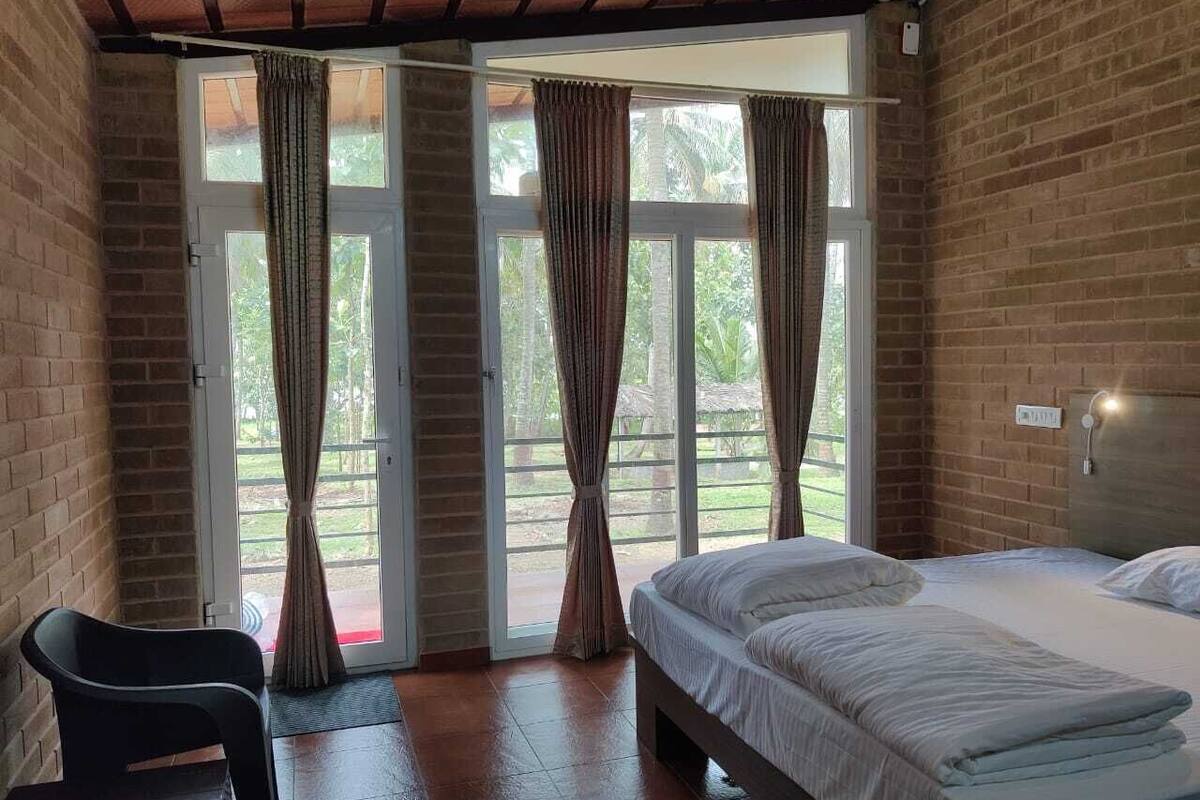 A room with a bed, a chair, and a sliding glass door leading to an outdoor area.