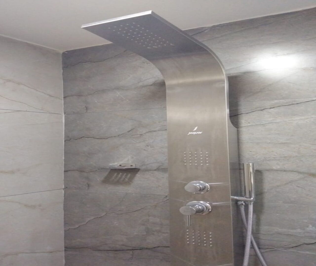 A modern shower with a curved design, a handheld showerhead, and a wall-mounted control panel.