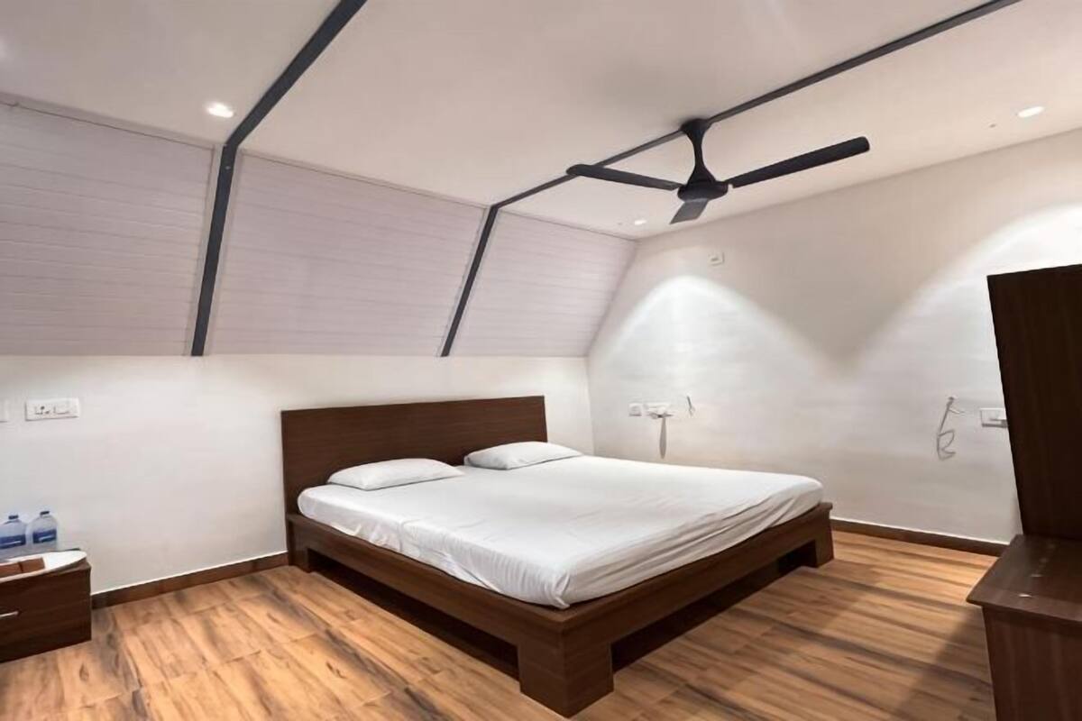 A bedroom with a wooden bed, a ceiling fan, and a wooden floor.