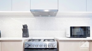 Een moderne keuken met een gasfornuis, een magnetron en een roestvrijstalen afzuigkap.