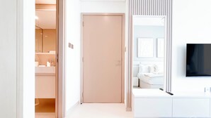 Een moderne hotelkamer met een badkamer, een grote spiegel, een flatscreen-tv en een witte console.