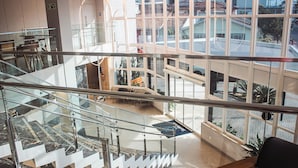 Un interior de varios niveles con barandillas de cristal, una escalera de mármol y vistas al exterior.