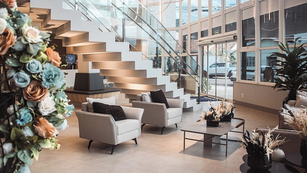 Un interior moderno con escalera, zona de estar y ventanas amplias.