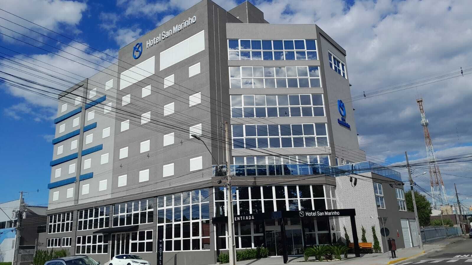 Un hotel de varios pisos con un diseño moderno, que presenta una entrada destacada y varias ventanas.