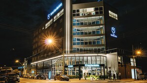 Un hotel moderno con una entrada destacada, varios pisos y una fachada bien iluminada.