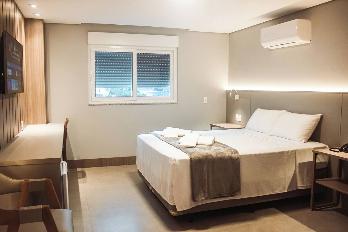 Una habitación de hotel moderna con cama, mesita de noche y escritorio con silla.