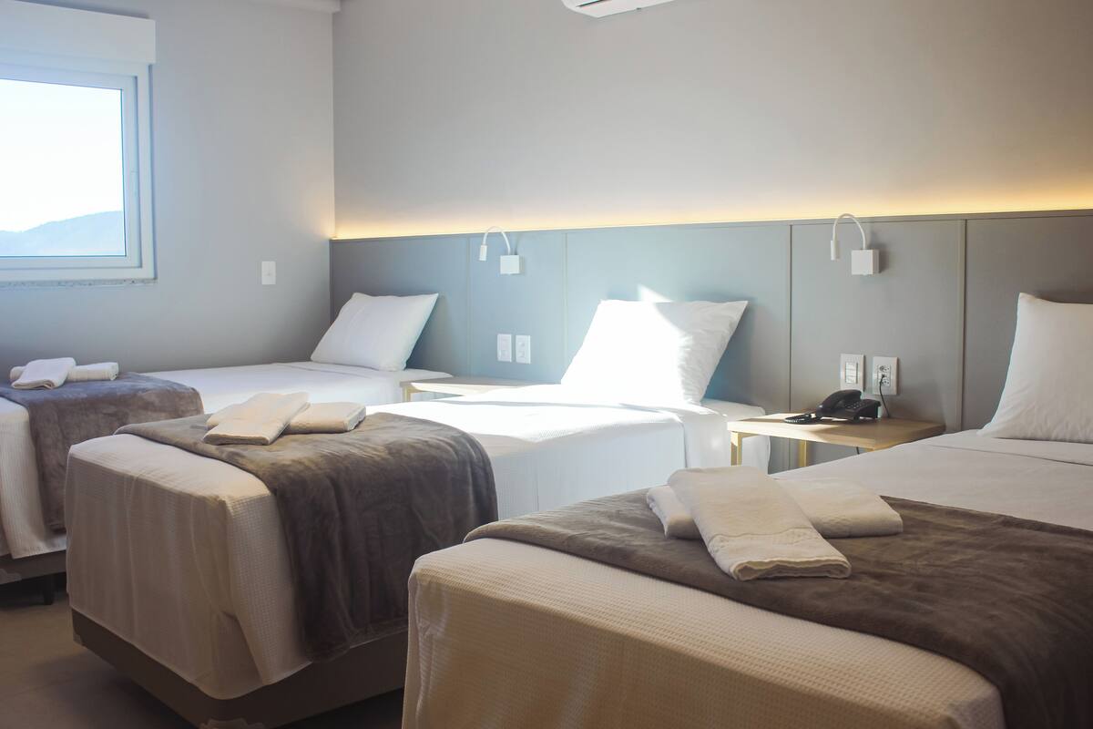 Habitación de hotel con dos camas, una mesita de noche, una lámpara y un teléfono.