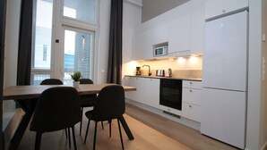 Une cuisine moderne avec des meubles blancs, un four à micro-ondes, un réfrigérateur et un coin repas comprenant une table et des chaises.