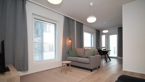 Un salon moderne avec un canapé, une petite table et un téléviseur.