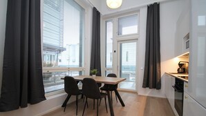 Une cuisine moderne avec un coin repas, de grandes fenêtres équipées de stores et une vue sur la ville.