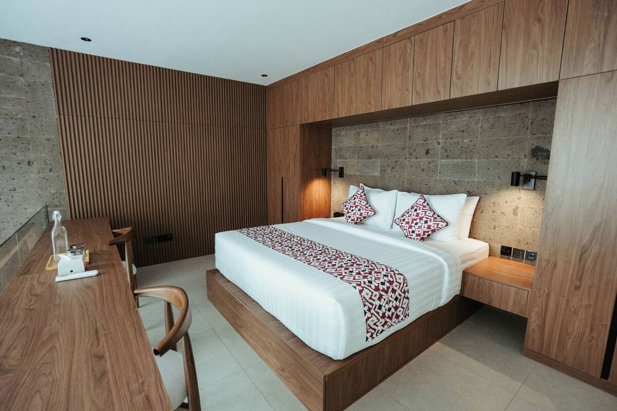 Ein modernes Schlafzimmer mit einem Holzbett, Nachttischen und einem Schreibtisch mit Stuhl.