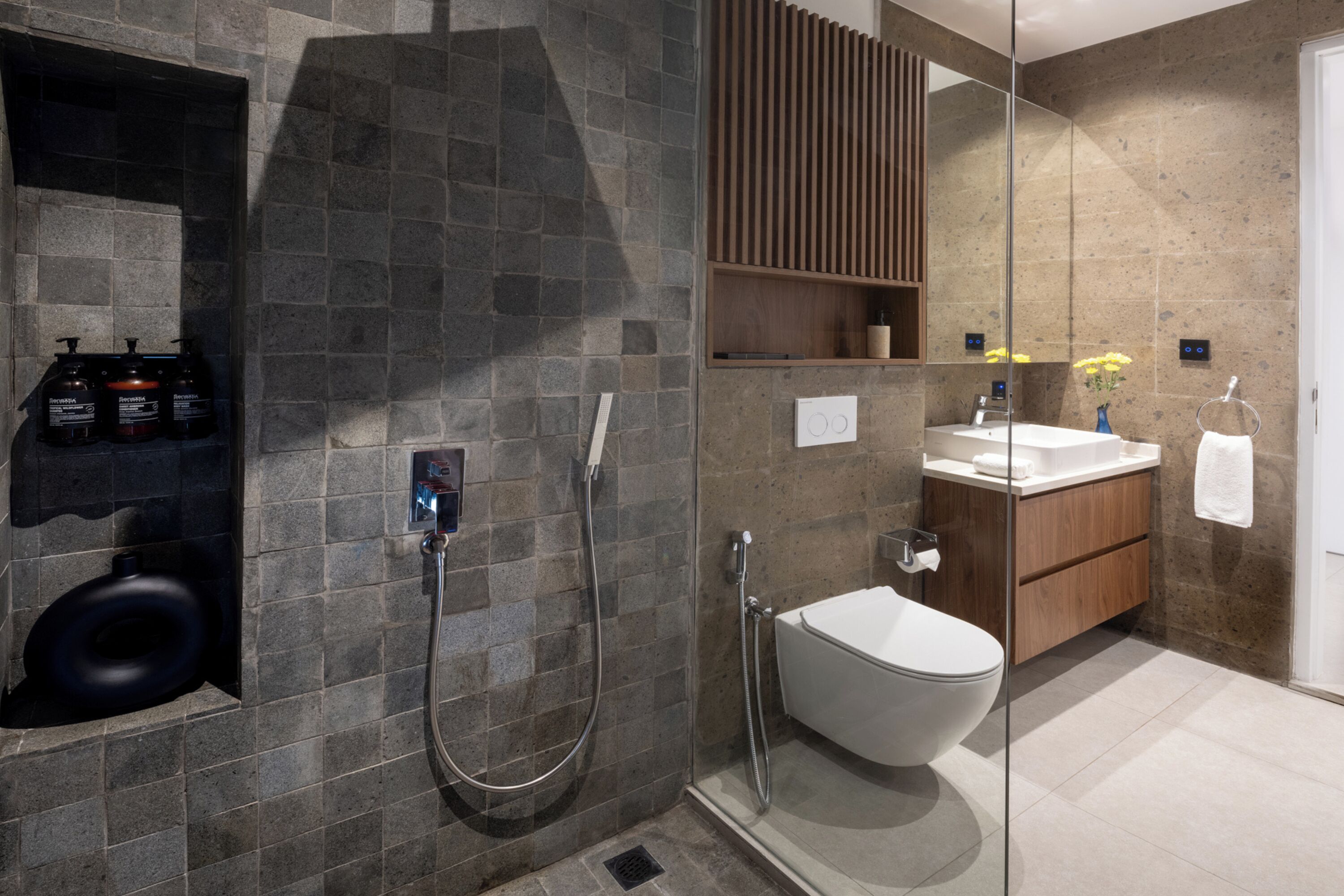 A modern bathroom with a glass-enclosed shower, a toilet, and a vanity with a mirror.