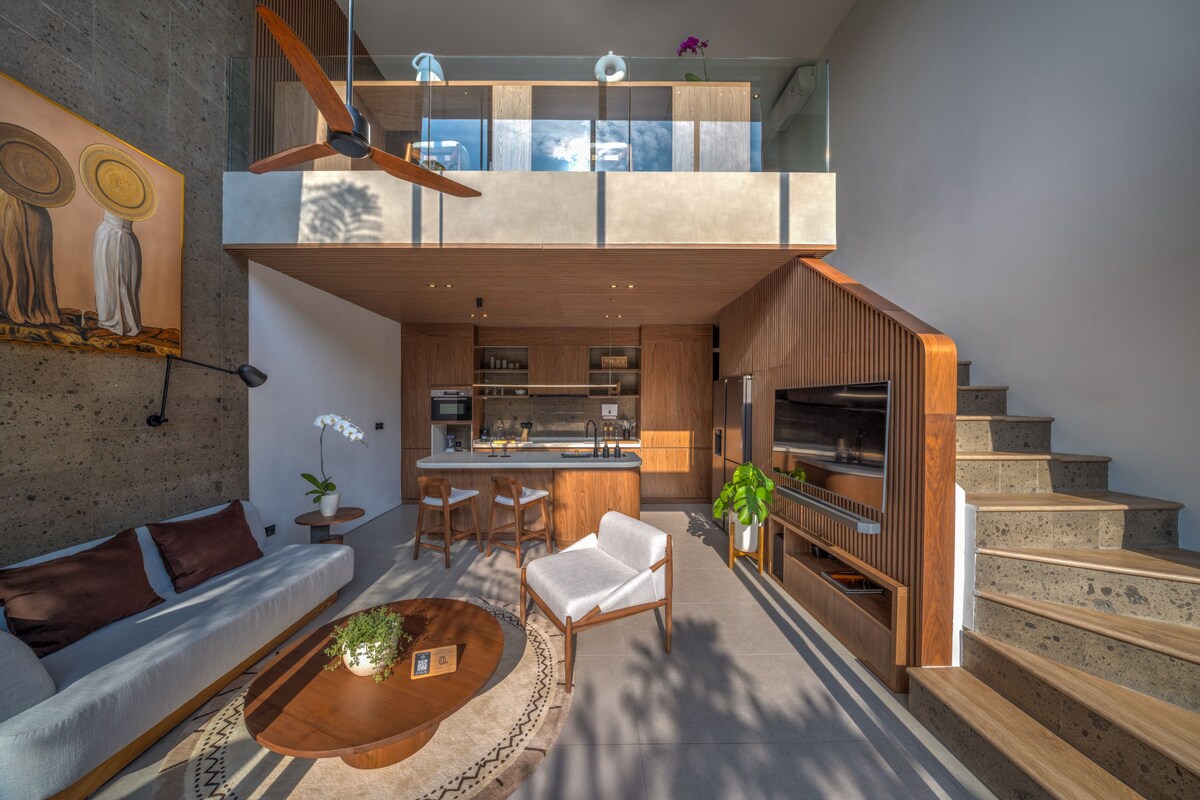 A modern interior with a kitchen, dining area, and a staircase leading to an upper level.