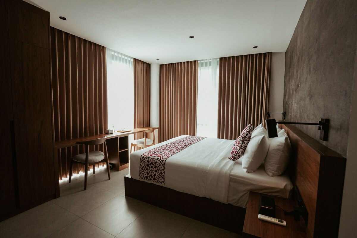 Een moderne slaapkamer met een groot bed, een bureau en een stoel.
