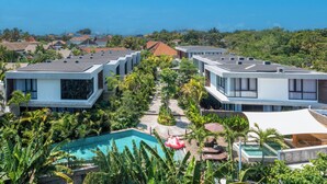Un moderno resort con varias edificaciones, una piscina central y exuberante vegetación.