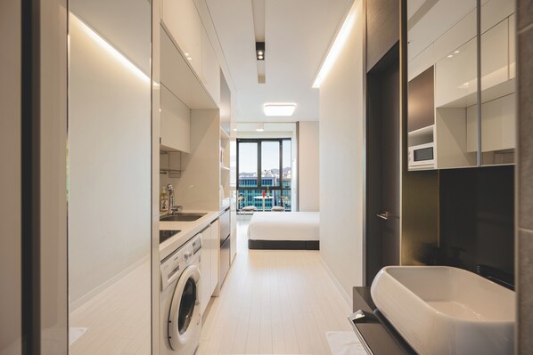 A modern bathroom with a bathtub, a washing machine, and a view of a balcony.