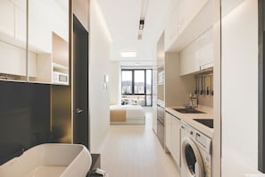 A modern kitchen with a washing machine, a microwave, and a sink.