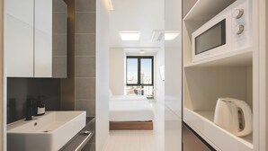 A modern hotel room with a large bed, a white sink, a microwave, and a kettle. - Gemstay Seomyeon (Busan)