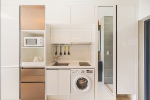 A compact kitchen with a microwave, sink, and washing machine.