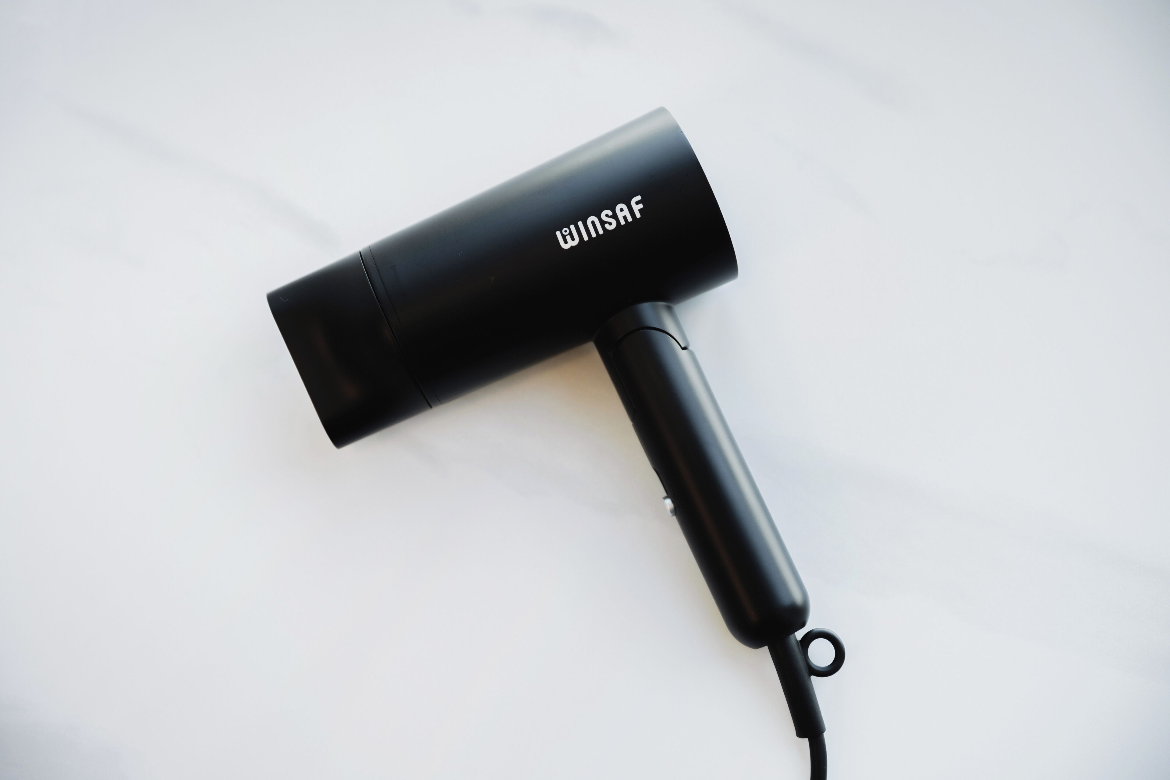 A black hairdryer with the brand name "WINSAF" on a white surface.
